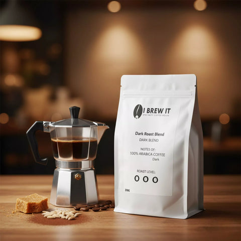 Dark Roast Blend 250g bag with espresso/moka scene on wooden table, warm bokeh, cinder toffee shard, cocoa dust and malt kernels.